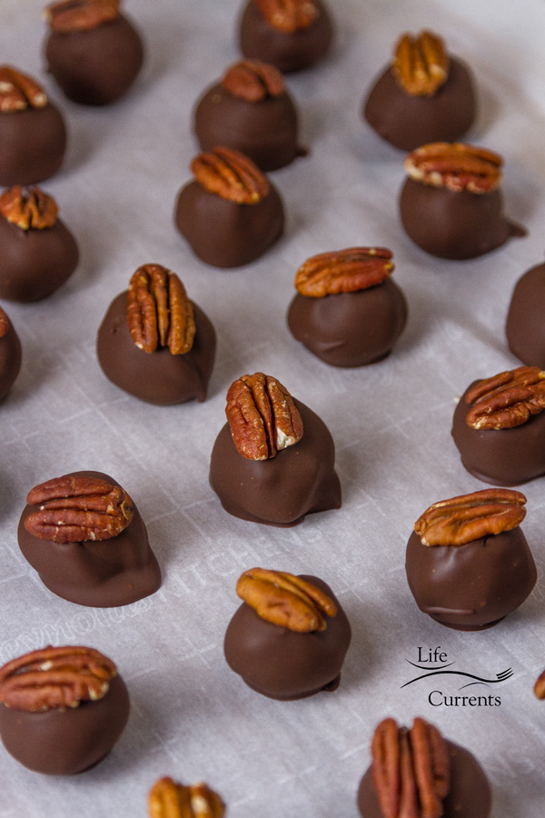 chocolate dipped and topped with a pecan, several Pecan Bourbon Balls on a tray