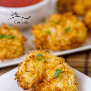breaded shrimp on a white plate in front of another white plate with more shrimp and some dipping sauce on it