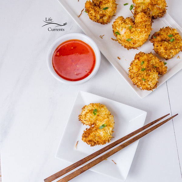 Air Fryer Coconut Shrimp with red dipping sauce on a white background with wooden chopsticks