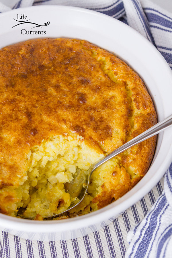 corn casserole with a serving taken out on a blue cloth 