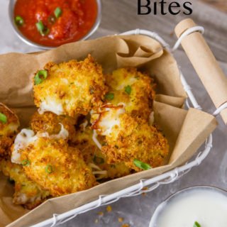 mozzarella pieces coated in bread crumbs air fried in a wire basket with a brown paper liner served with small aluminium ramekins of marinara sauce and ranch dressing garnished with green onions