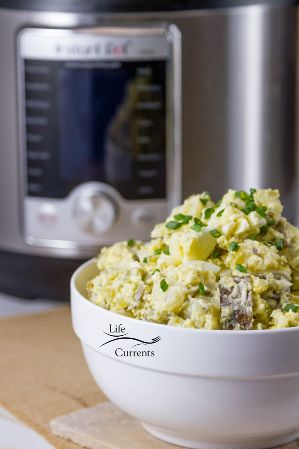 Potato salad in a white bowl in front of an Instant Pot multicooker 