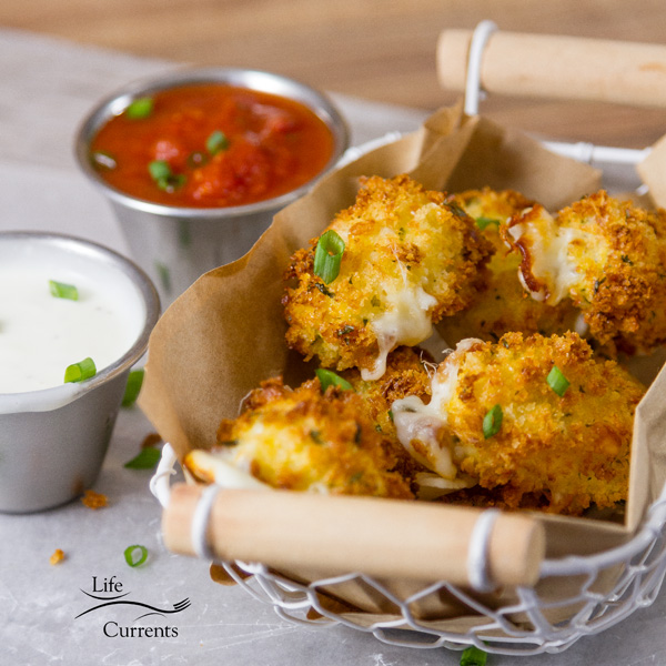 Crispy on the outside, cheesy and ooey gooey on the inside, these Air Fryer Mozzarella Bites are super easy to make and even easier to eat! Serve them as an appetizer or as a side dish, and since their made in the air fryer they have fewer calories and less fat, and no guilt. These are a must try! Air fryer mozzarella bites served in a wire basket with wooden handles along with ranch and marinara for dipping