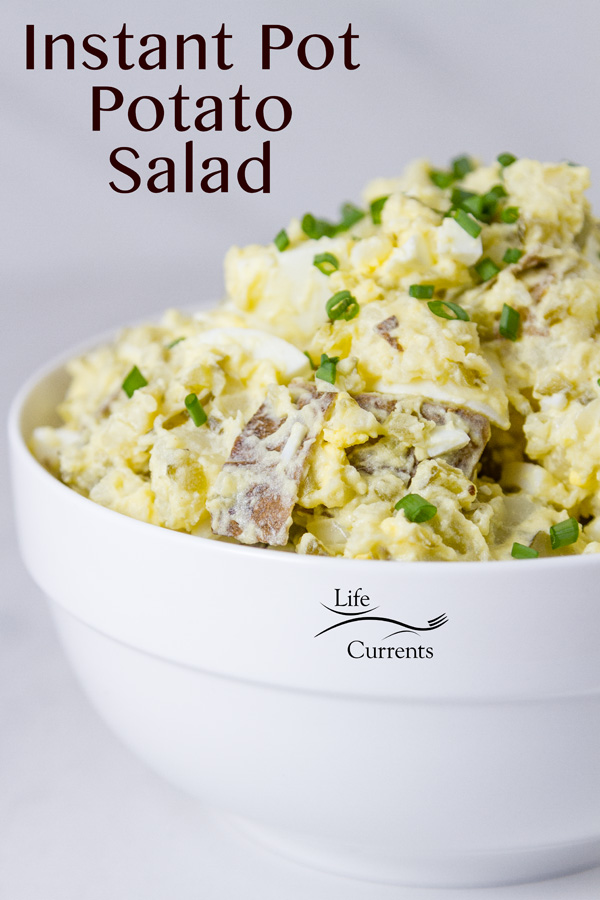 Potato salad in a white bowl on a white background topped with chives and the title is on the image 