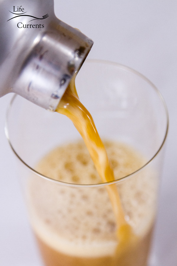 pouring the iced shaken coffee from the cocktail shaker into a glass on a white background