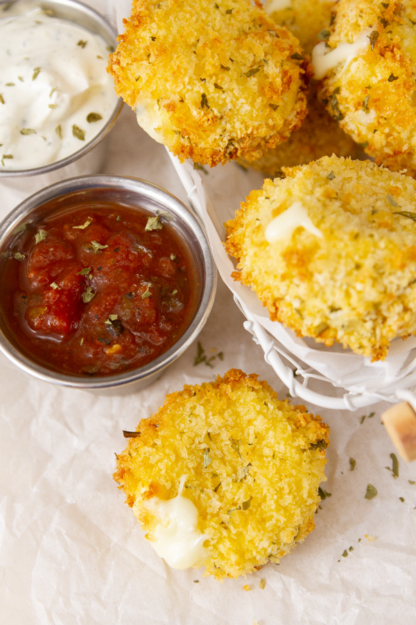 looking down on cooked Air Fryer Babybel cheese on parchment paper with marinara sauce and ranch.