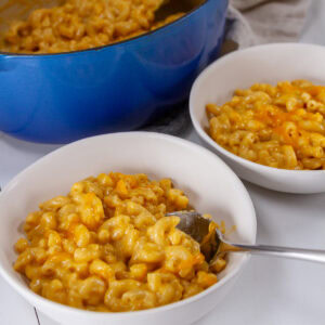 two bowls of mac & cheese in front of the casserole dish.