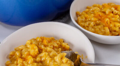 two bowls of mac & cheese in front of the casserole dish.