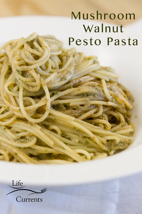 Spaghetti noodles with mushroom basil walnut pesto served in a white bowl