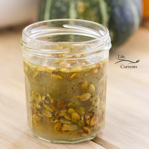 Toasted Pumpkin Seed Vinaigrette in a jar with a green squash in the background