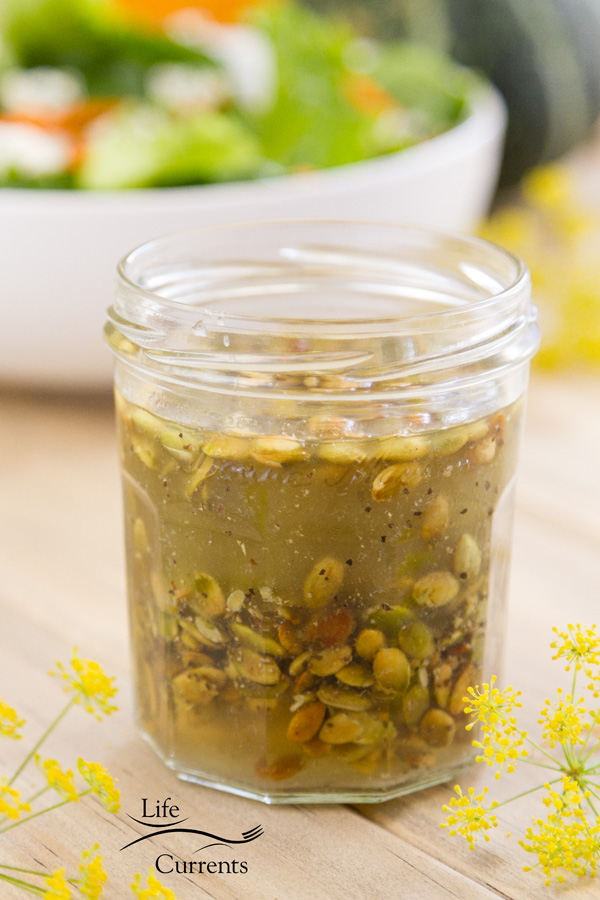 Toasted Pumpkin Seed Vinaigrette in a glass jar with a green salad 
