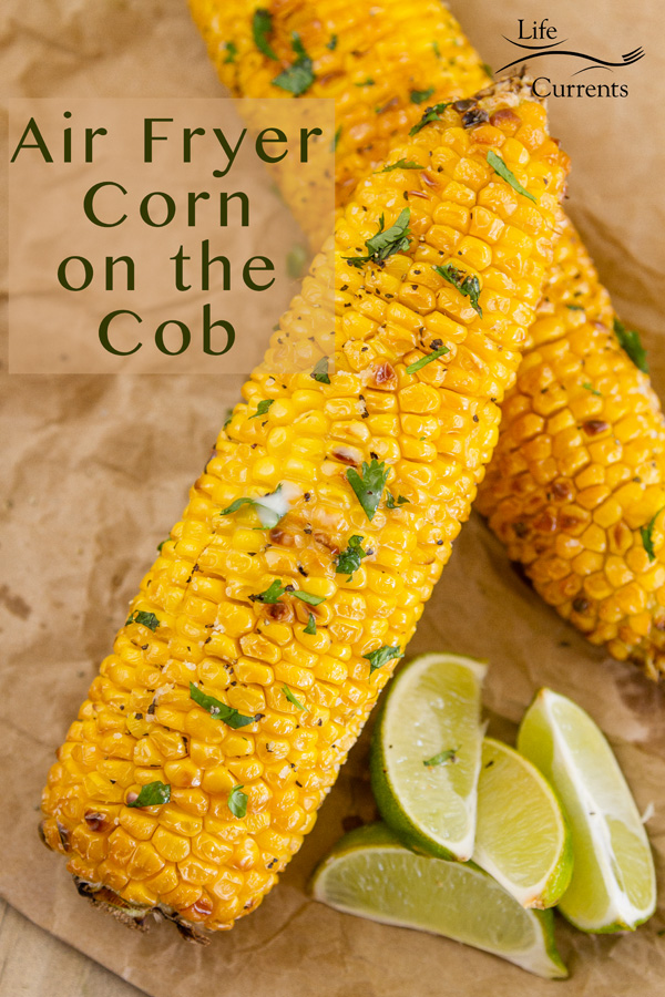 roasted corn on the cob with green herbs for garnish and lime wedges on a brown paper bag background