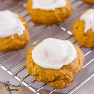 four iced pumpkin cookies on a cooling rack