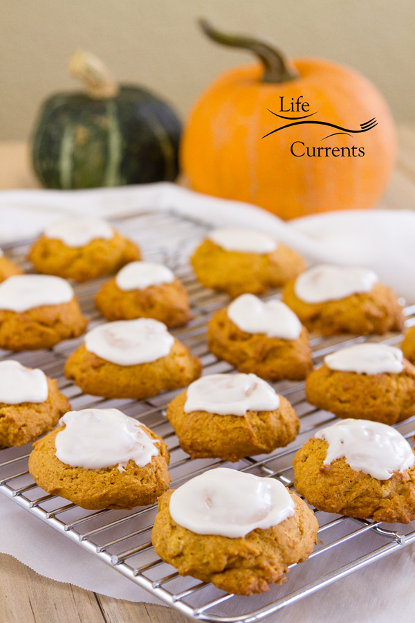 orange pumpkin cookies iced and cooling on a rack with a green and an orange pumpkin in the background 