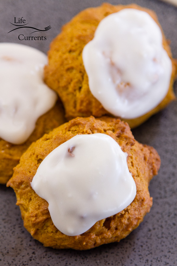 Three iced pumpkin cookies on a blackplate