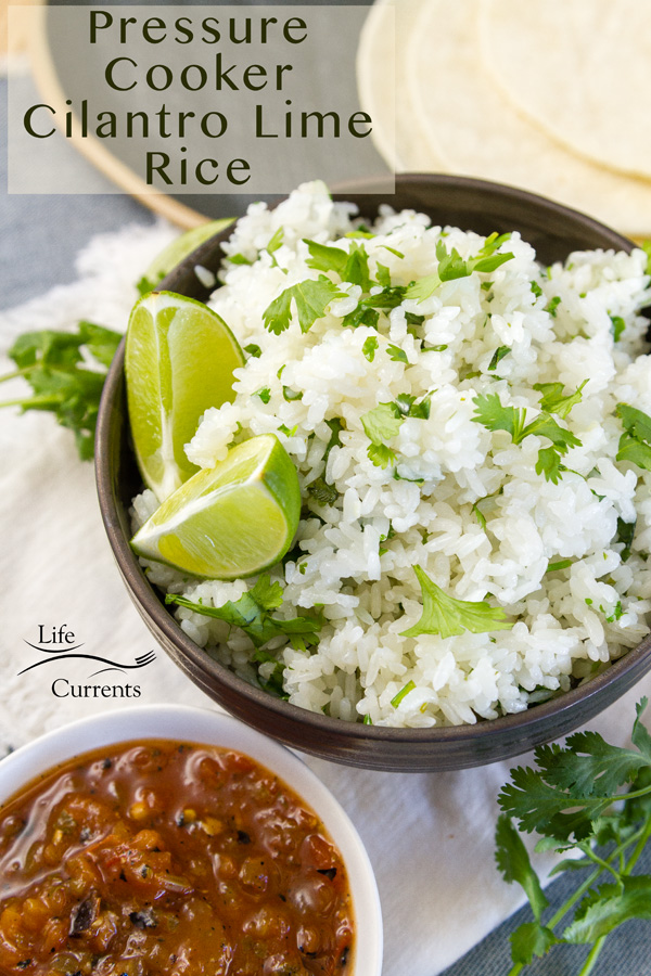 a bowl full of cilantro lime rice with wedges of lime served with salsa and corn tortillas