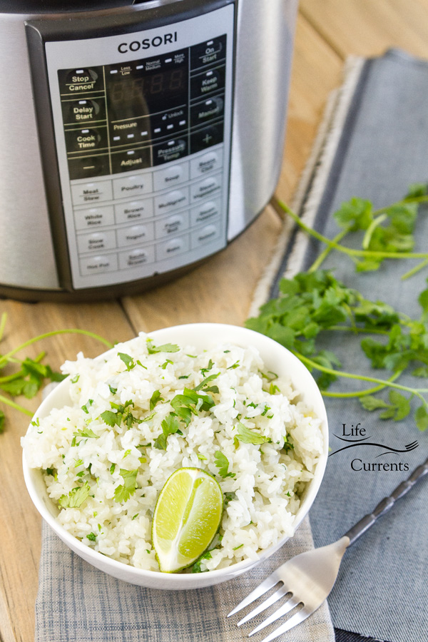 a pressure cooker with a bow of rice some cilantro stems, a fork, and 2 cloth napkins 