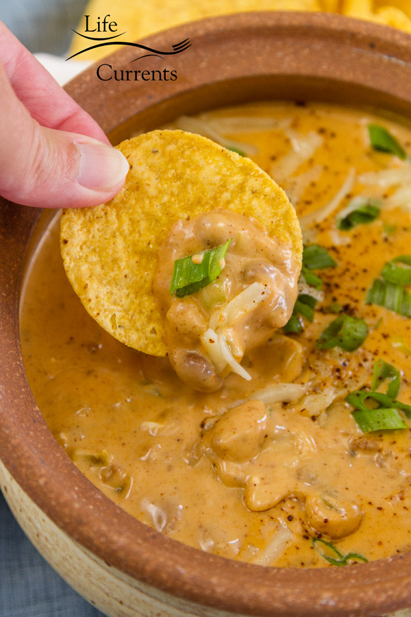 dipping a chip into the Mexican Chili Cheese Dip 