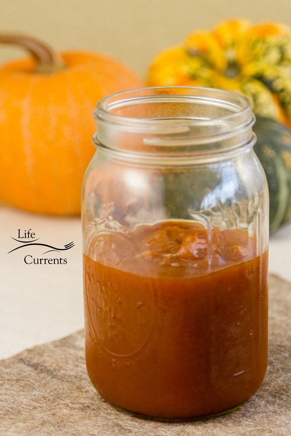 pumpkin butter in a jar in front of squashes 