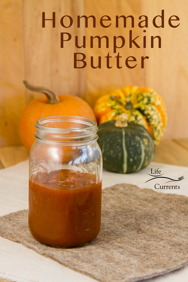 a jar of pumpkin butter in front of some squash on a brown felt pad