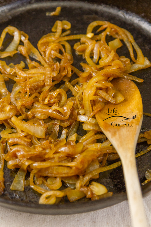 caramelized onions in a cast iron skillet with a wooden spoon