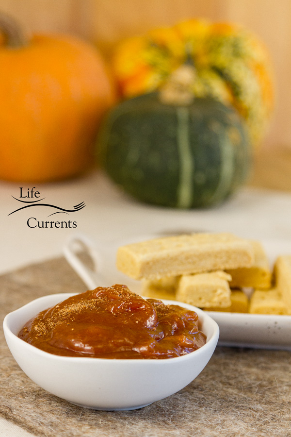 fruit butter in a dish with shortbread cookies and some pumpkins in the background 