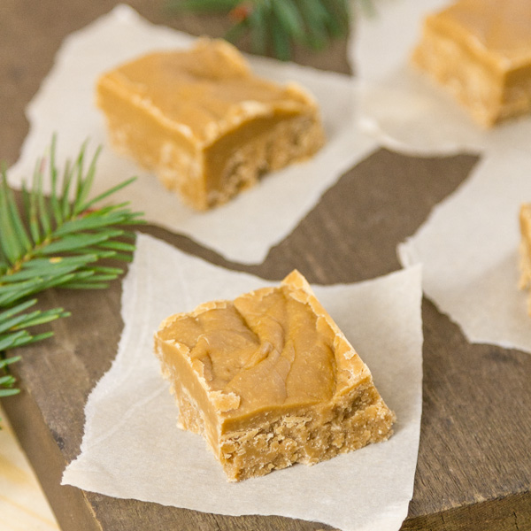 This buttery melt-in-your-mouth delicious old-fashioned Brown Sugar Fudge has the warm flavor of caramel and reminds me of a fabulous New Orleans praline. It’s perfect on a Christmas dessert tray or included in a cookie exchange. You'll want to keep this recipe handy, as gift giving season approaches. square crop of brown suagr fudge on pieces of parchment paper on a wooden background with fir tree branches