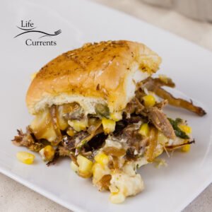 carnitas sliders sandwich with corn and cheese on a white plate