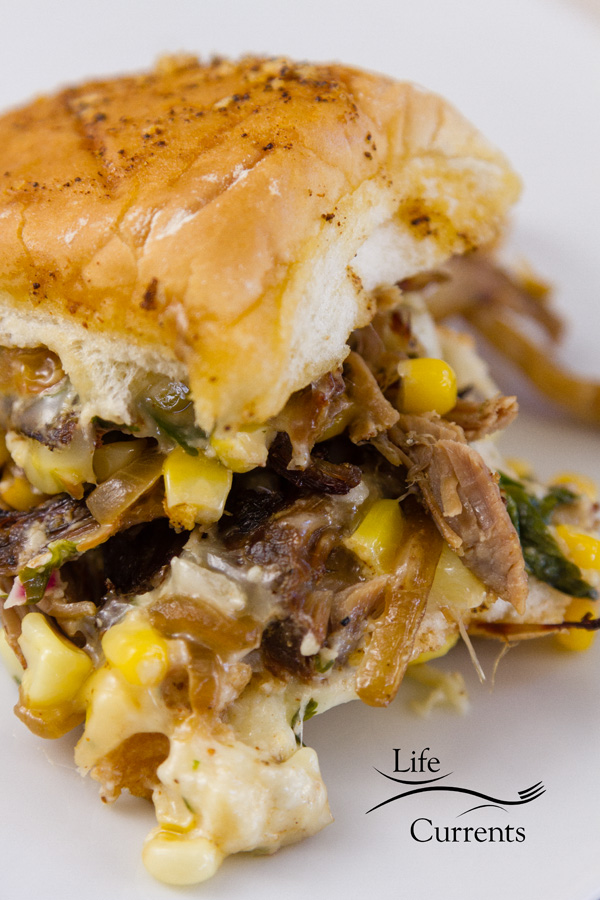 a close up on the carnitas slider sandwich with Mexican Street Corn (esquites), caramelized onions, and cheese 
