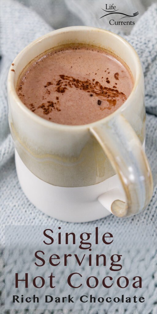 A mug filed with hot cocoa on a light blue knitted cloth 