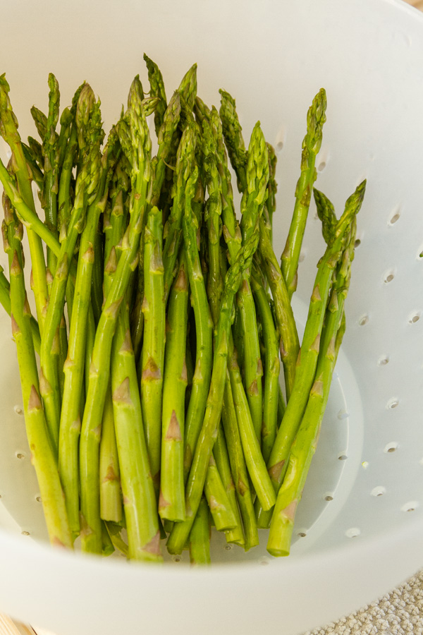 Air Fryer Asparagus - Asparagus is so simple to prepare, and it’s one of my favorite healthy veggies. How to Roast Asparagus in the Air Fryer makes it even easier than in the oven, the quick and easy way to cook this earthy and delicious green veggie. asparagus being cleaned in a white colander