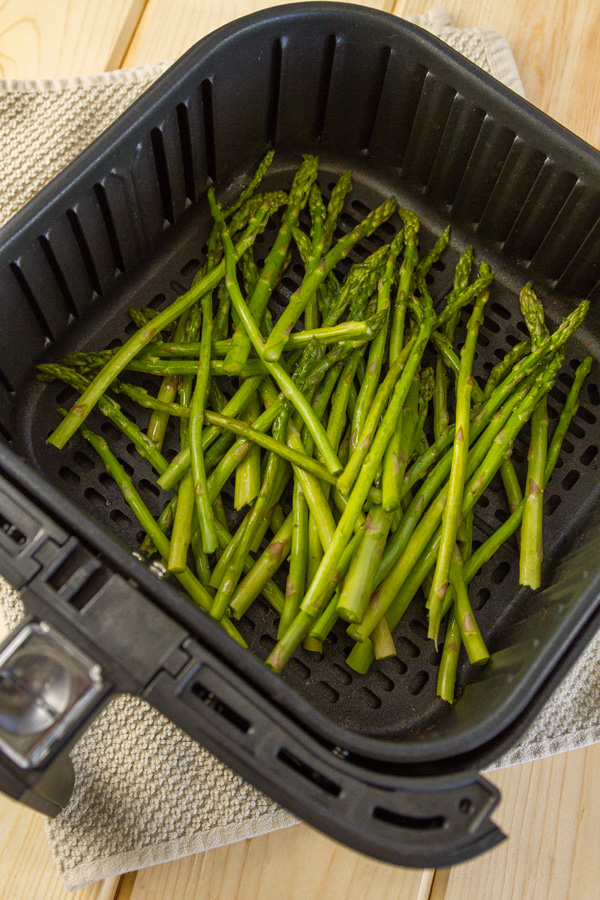 Cooking asparagus in the air fryer requires just 2 simple ingredients (plus salt and pepper), and is ready in a fraction of the time that it would take to oven roast it. This Air Fryer Roasted Asparagus will be your favorite way to cook asparagus from now on! asparagus in the air fryer basket ready to cook