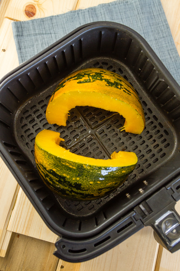 squash wedges in the basket of an air fryer.