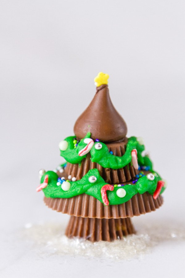 one christmas tree made from peanut butter cups and a hershey's kiss decorated with icing and sprinkles on a white background