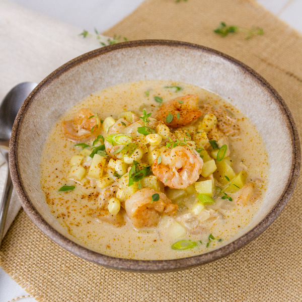 This Cajun Seafood Chowder is rich and creamy, with just the right amount of Cajun spiced seafood including shrimp and tuna, along with sweet corn and earthy potatoes. It’s perfect comfort food that will make you happy square crop of a white bowl with Cajun seafood chowder