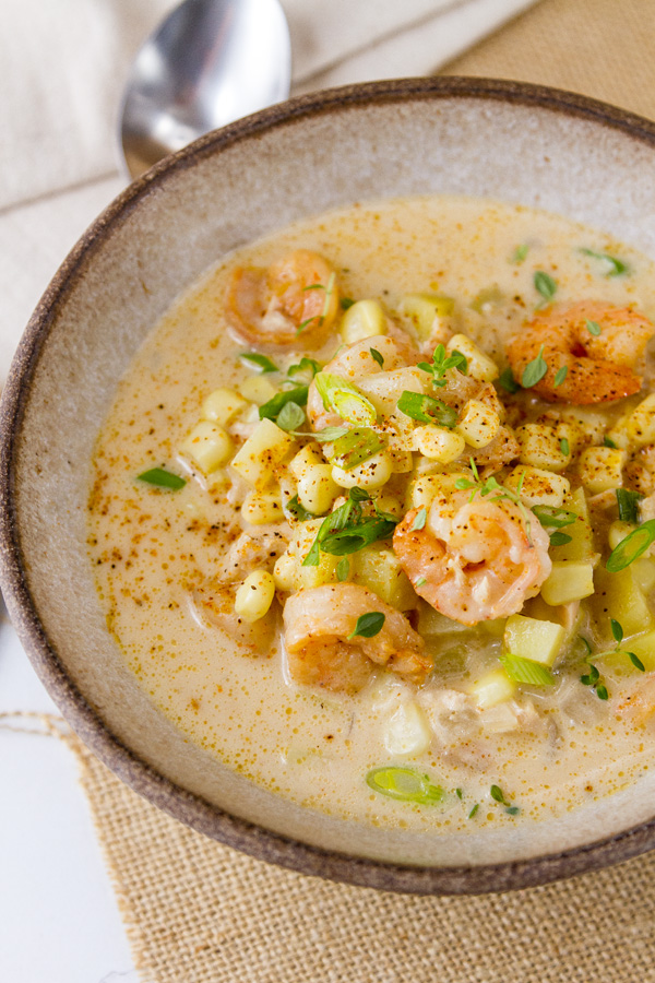This Cajun Seafood Chowder is rich and creamy, with just the right amount of Cajun spiced seafood including shrimp and tuna, along with sweet corn and earthy potatoes. It’s perfect comfort food that will make you happy a white bowl with a spoon to serve Cajun Seafood chowder