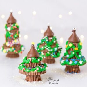 square crop of 4 peanut butter cup Christmas trees with twinkle lights in background