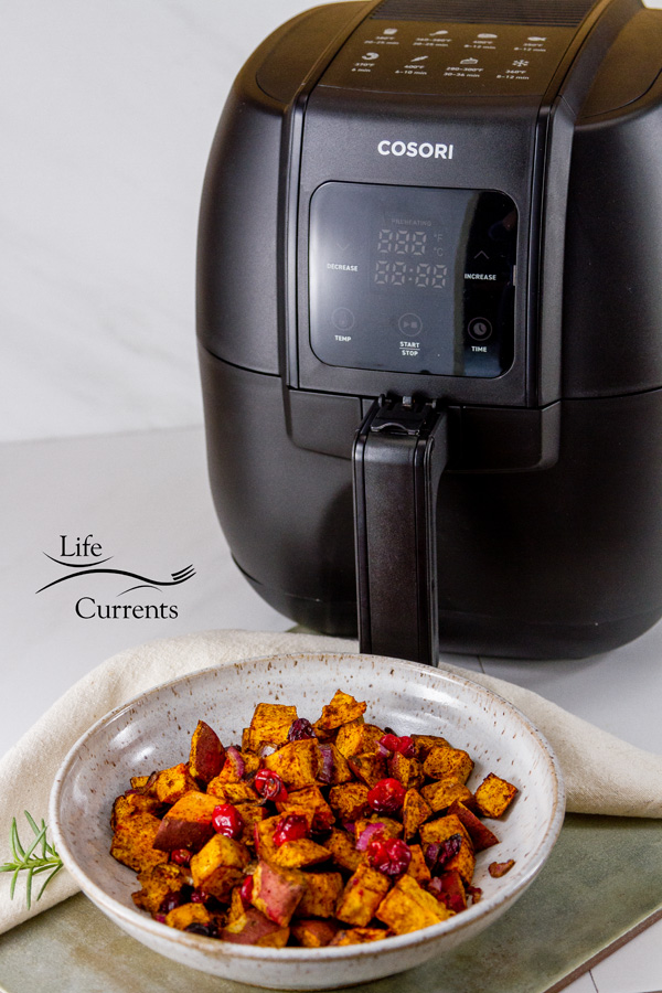 The COSORI Air Fryer behind a bowl full of roasted sweet potatoes 