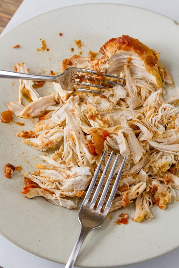 two forks shredding salsa chicken on a plate