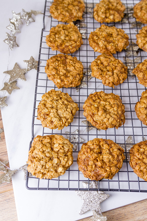 Crispy edges, chewy in the middle, and wholesome perfectly balanced Famous Oatmeal Cookies. These are my favorite cookies, and they are the classic original recipe! So good, they’re famous. In fact, this is the original recipe from the side of the oatmeal carton that my mom always made when I was a kid. a rack of oatmeal cookies with silver glitter stars behind