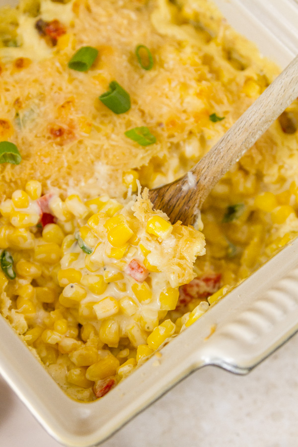 Corn side dish in a servings dish with a wooden spoon 
