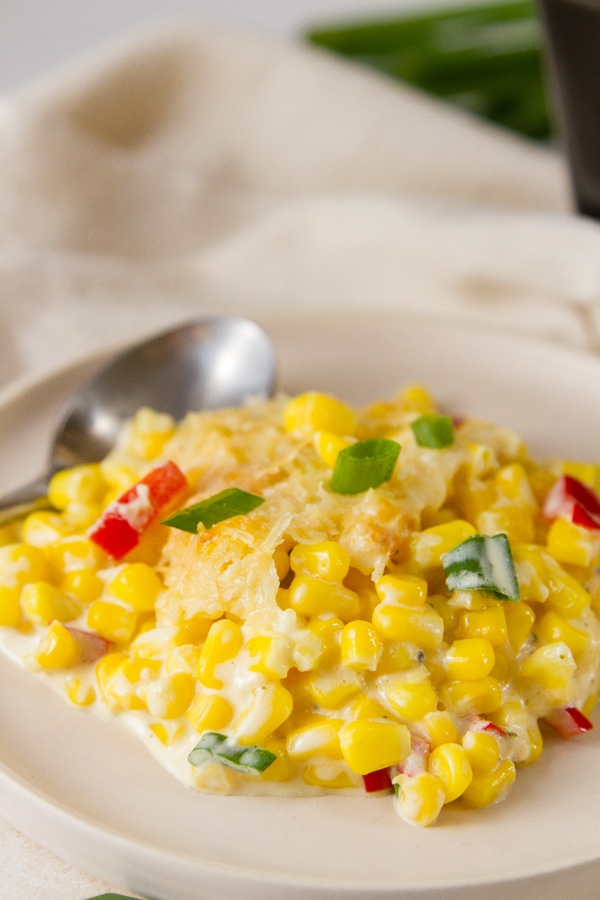 A seving of creamed corn on a plate with a spoon