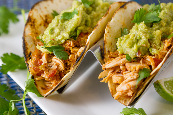 two tortillas filled with shredded chicken and guacamole topped with cilantro.