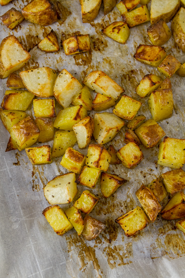 Sheet Pan Roasted Potatoes are an easy, delicious side dish for any meal. This super easy method produces perfectly cooked potatoes that are crispy outside and tender and creamy inside. Roasted Potatoes on a parchment paper