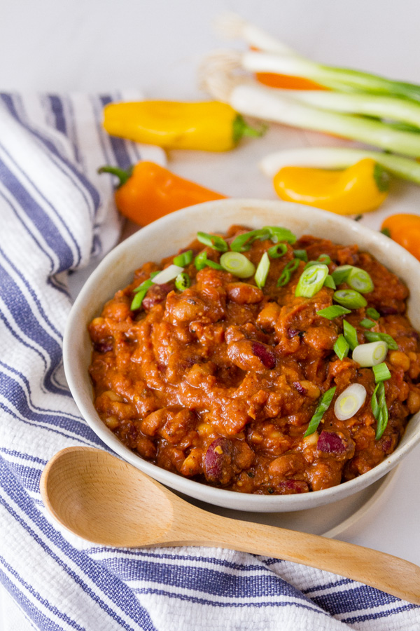 Crock Pot Vegetarian Chili in a bowl with a wooden spoon and a blue cloth 