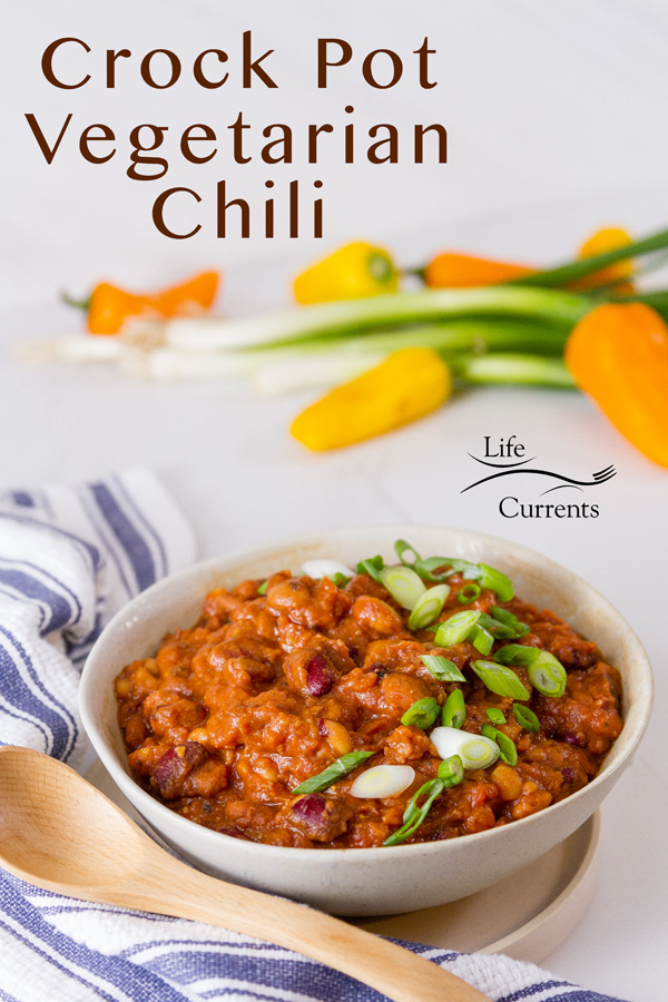 Crock Pot Vegetarian Chili in a bowl with a blue striped cloth and some vegetables in the background