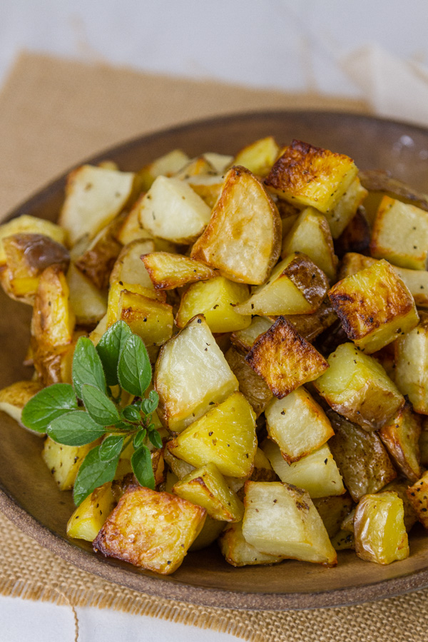 Sheet Pan Roasted Potatoes are an easy, delicious side dish for any meal. This super easy method produces perfectly cooked potatoes that are crispy outside and tender and creamy inside. Sheet Pan Roasted Potatoes in a brown bowl for servings
