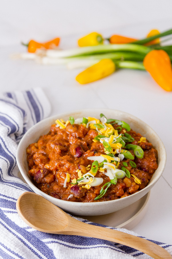 Crock Pot Vegetarian Chili with a blue striped cloth, peppers, and green onions