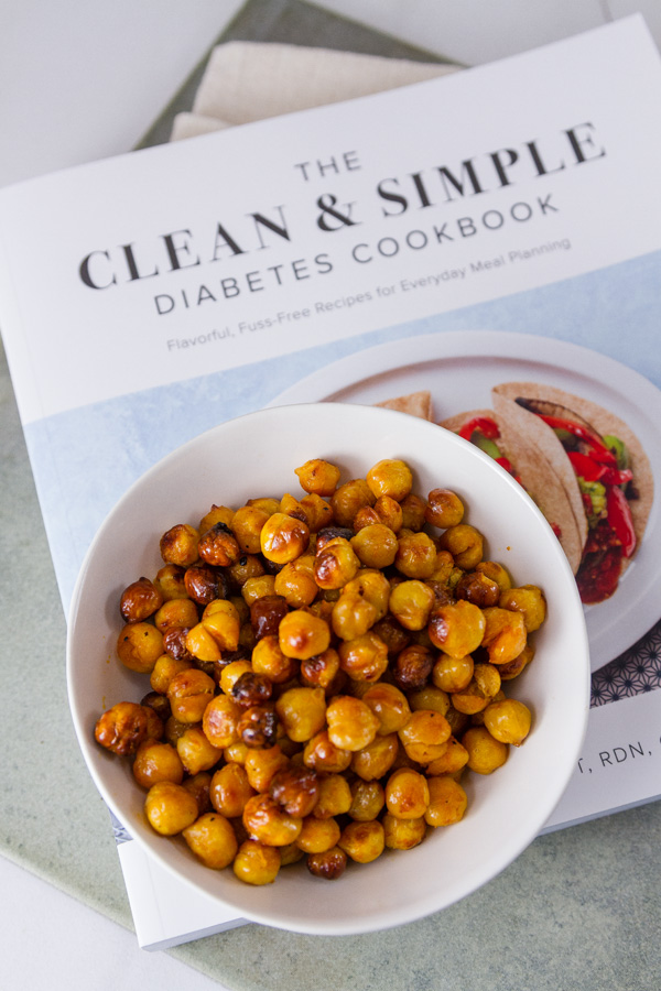 Buffalo Roasted Chickpeas in a white bowl on the book The Clean & Simple Diabetes Cookbook