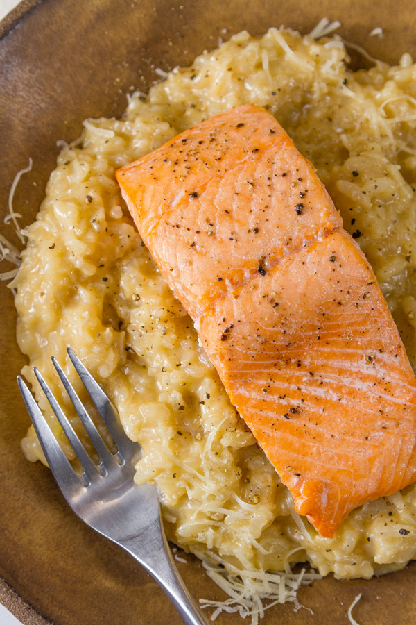Roasted Salmon Risotto with a fillet of salmon over the risotto on a brown plate 